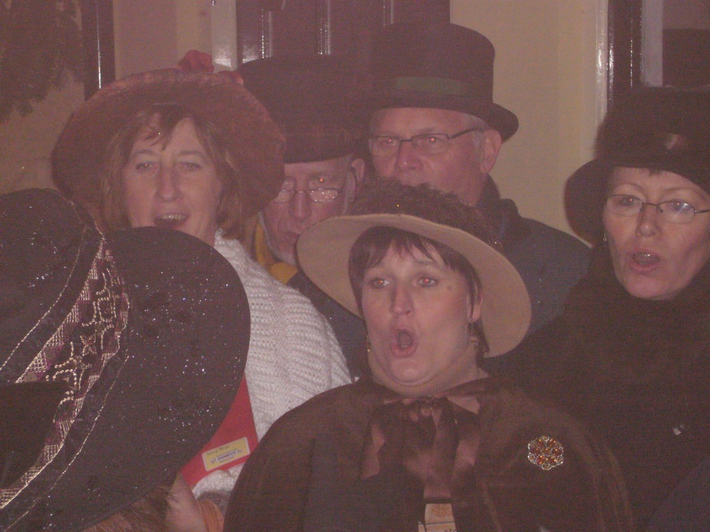 Actors in Victorian clothing singing at a square in the city center, during the Dickens Festival, at sunset