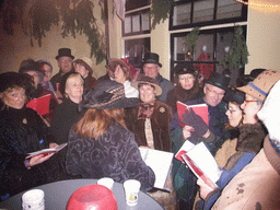 Actors in Victorian clothing singing at a square in the city center, during the Dickens Festival, at sunset