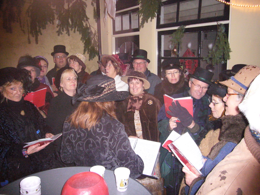 Actors in Victorian clothing singing at a square in the city center, during the Dickens Festival, at sunset