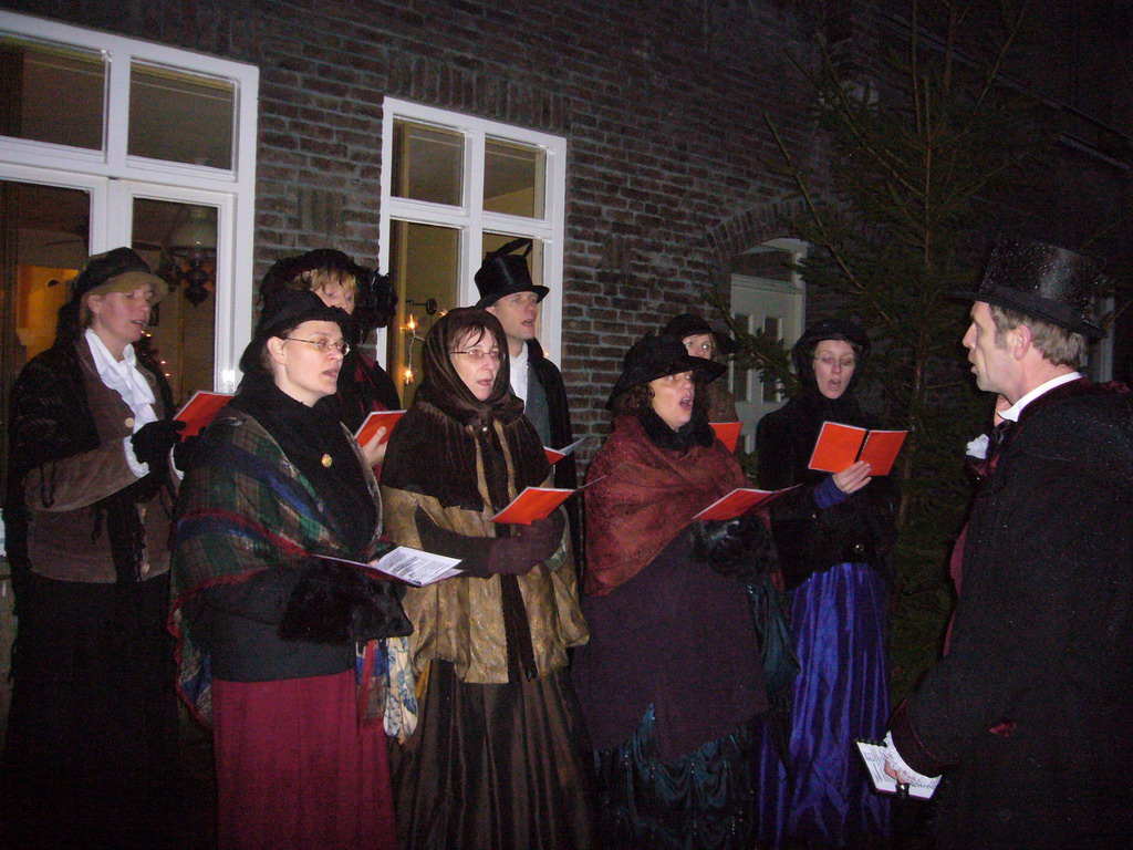 Actors in Victorian clothing singing at a square in the city center, during the Dickens Festival, at sunset