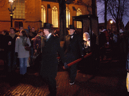 Actors in Victorian clothing in front of the St. Nicholas Church at the Bergkerkplein square, during the Dickens Festival parade, by night