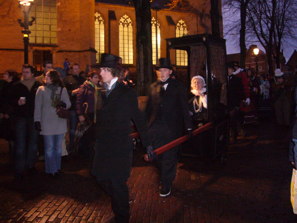 Actors in Victorian clothing in front of the St. Nicholas Church at the Bergkerkplein square, during the Dickens Festival parade, by night