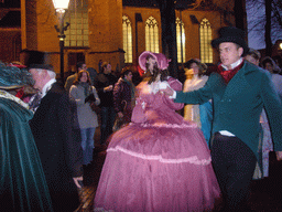 Actors in Victorian clothing in front of the St. Nicholas Church at the Bergkerkplein square, during the Dickens Festival parade, by night