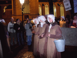 Actors in Victorian clothing in front of the St. Nicholas Church at the Bergkerkplein square, during the Dickens Festival parade, by night