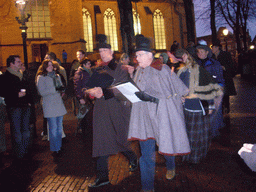 Actors in Victorian clothing in front of the St. Nicholas Church at the Bergkerkplein square, during the Dickens Festival parade, by night