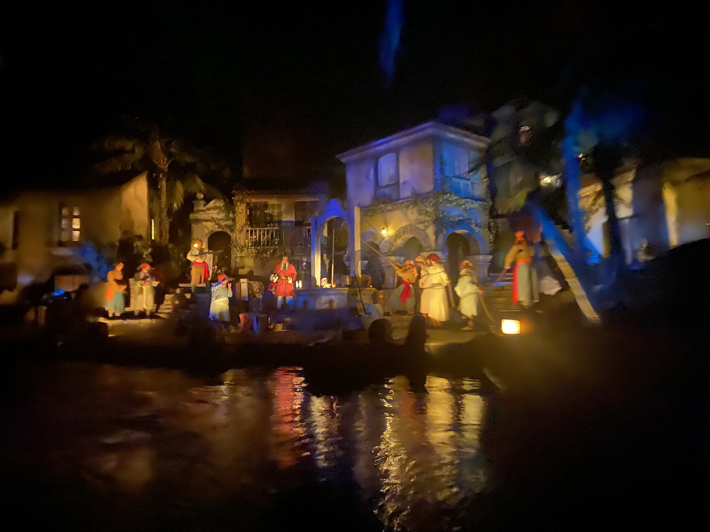 Pirate statues at a well at the Pirates of the Caribbean attraction at Adventureland at Disneyland Park, viewed from our boat, by night