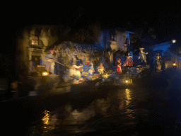 Salesman statues at a market at the Pirates of the Caribbean attraction at Adventureland at Disneyland Park, viewed from our boat, by night