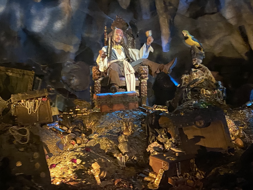 Statues of Captain Jack Sparrow and a parrot on a treasure at the Pirates of the Caribbean attraction at Adventureland at Disneyland Park, viewed from our boat, by night