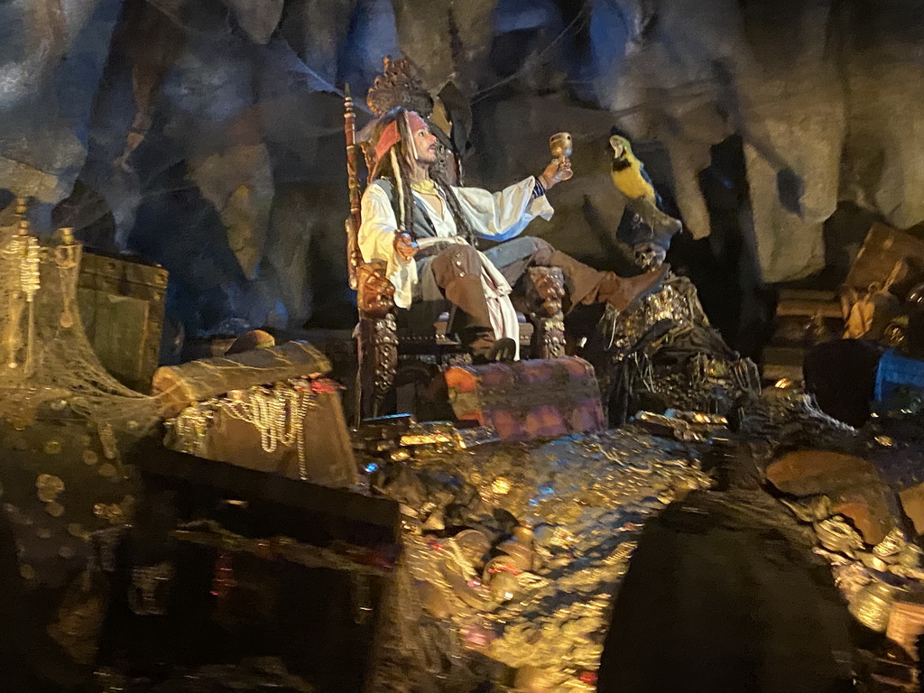 Statues of Captain Jack Sparrow and a parrot on a treasure at the Pirates of the Caribbean attraction at Adventureland at Disneyland Park, viewed from our boat, by night