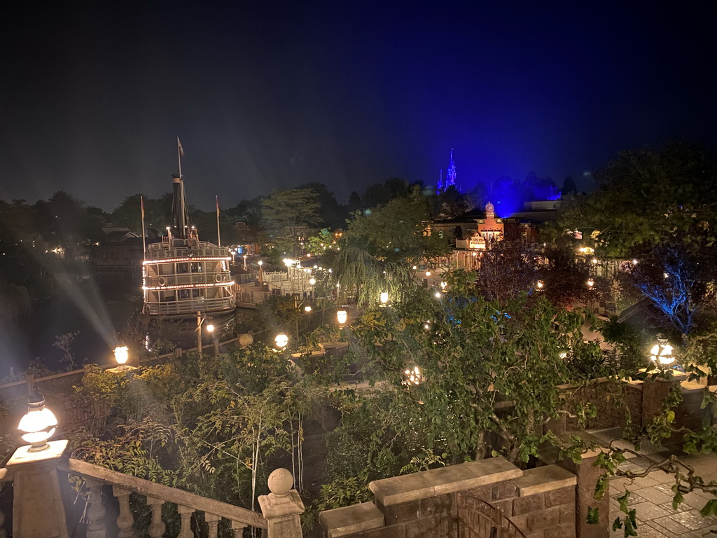 The Thunder Mesa Riverboat Landing attraction and the Silver Sput Steakhouse restaurant at Frontierland and Sleeping Beauty`s Castle at Fantasyland at Disneyland Park, viewed from the staircase to the Phantom Manor attraction at Frontierland, by night