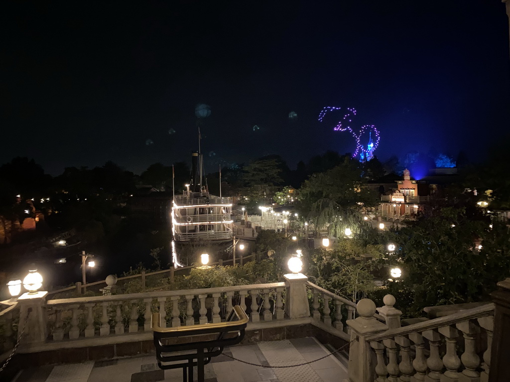 The Thunder Mesa Riverboat Landing attraction and the Silver Sput Steakhouse restaurant at Frontierland and Sleeping Beauty`s Castle at Fantasyland at Disneyland Park, viewed from the staircase to the Phantom Manor attraction at Frontierland, during the Disney D-Light drone show, by night