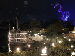 The Thunder Mesa Riverboat Landing attraction and the Silver Sput Steakhouse restaurant at Frontierland and Sleeping Beauty`s Castle at Fantasyland at Disneyland Park, viewed from the staircase to the Phantom Manor attraction at Frontierland, during the Disney D-Light drone show, by night