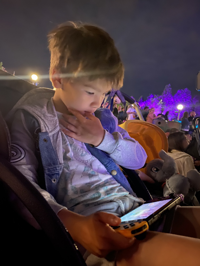 Max playing on the Nintendo Switch at Central Plaza at Disneyland Park, by night