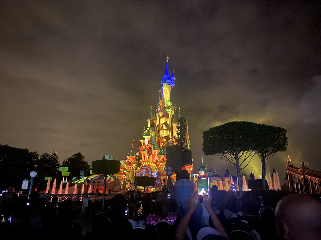 Front of Sleeping Beauty`s Castle at Fantasyland at Disneyland Park, with illuminations and fountains during the Disney Illuminations show, viewed from Central Plaza, by night