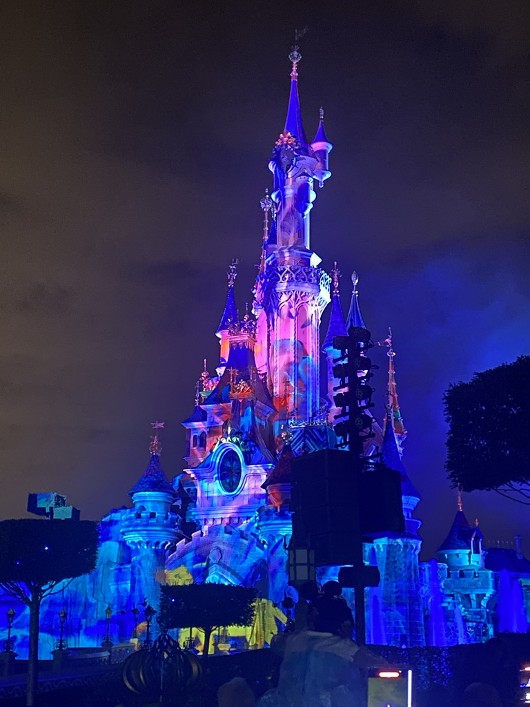 Front of Sleeping Beauty`s Castle at Fantasyland at Disneyland Park, with illuminations and fountains during the Disney Illuminations show, viewed from Central Plaza, by night