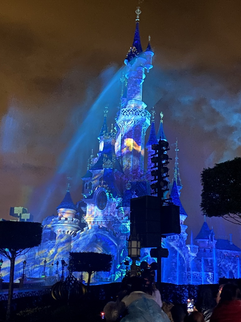 Front of Sleeping Beauty`s Castle at Fantasyland at Disneyland Park, with illuminations and fountains during the Disney Illuminations show, viewed from Central Plaza, by night