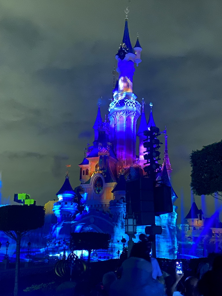 Front of Sleeping Beauty`s Castle at Fantasyland at Disneyland Park, with illuminations and fountains during the Disney Illuminations show, viewed from Central Plaza, by night