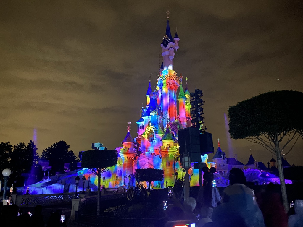 Front of Sleeping Beauty`s Castle at Fantasyland at Disneyland Park, with illuminations and fountains during the Disney Illuminations show, viewed from Central Plaza, by night