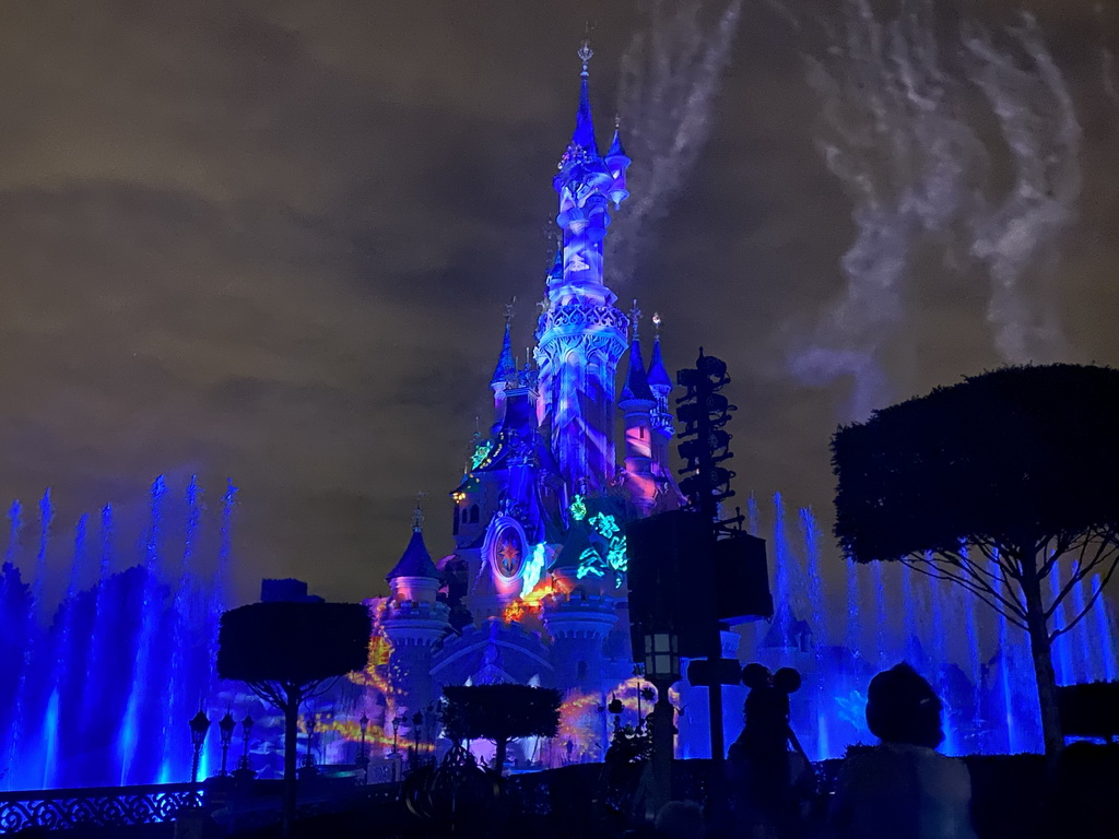 Front of Sleeping Beauty`s Castle at Fantasyland at Disneyland Park, with illuminations, fireworks and fountains during the Disney Illuminations show, viewed from Central Plaza, by night