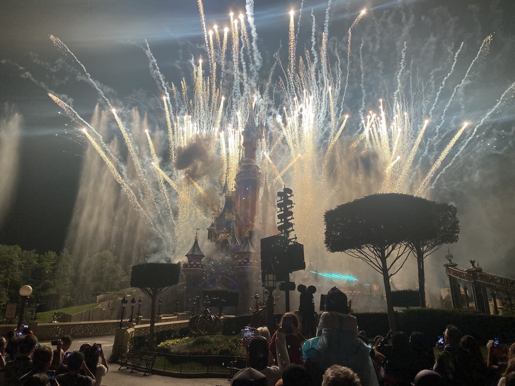 Front of Sleeping Beauty`s Castle at Fantasyland at Disneyland Park, with fireworks and fountains during the Disney Illuminations show, viewed from Central Plaza, by night