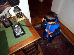 Max with an old telephone on a desk in a hallway at the upper floor of Castle Sterkenburg
