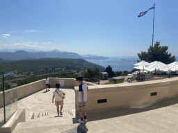 Miaomiao and Max walking to the terrace of the Restaurant Panorama at Mount Srd, with a view on the hills and mountains to the east