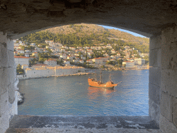 Window at the top of the Tvrdava Svetog Ivana fortress, with a view on an old ship and the east side of the city with the Lazareti Creative Hub of Dubrovnik, the Plaa Banje beach and the Hotel Excelsior