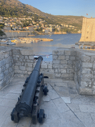 Cannon on top of the eastern city walls, with a view on the Old Port, the Tvrdava Svetog Ivana fortress and the east side of the city with the Lazareti Creative Hub of Dubrovnik, the Plaa Banje beach and the Hotel Excelsior