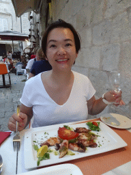 Miaomiao eating squid at the terrace of the Konoba Saint Blaise restaurant at the Zeljarica Ulica street