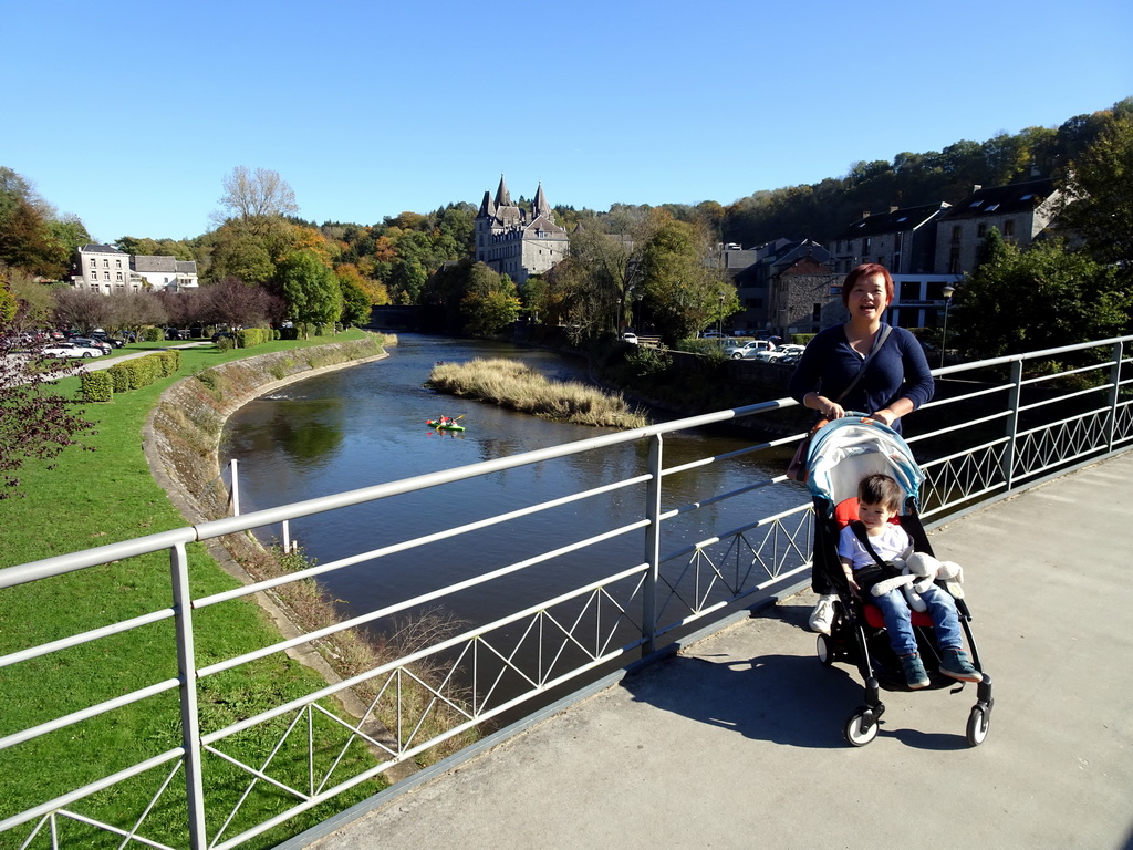 Miaomiao and Max at the pedestrian bridge at the west side of town, with a view on a canoe in the Ourthe river and the Durbuy Castle