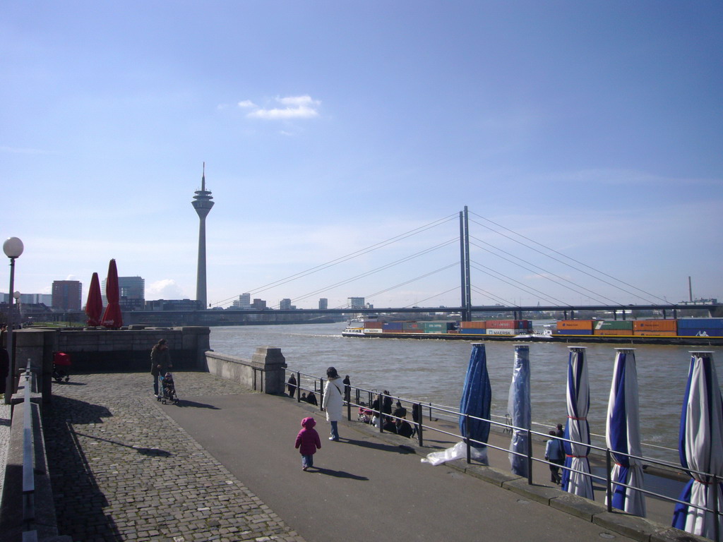 The Rhine shore, with a view on the Rheinturm Düsseldorf, Rheinkniebrücke bridge and a boat