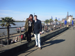 Tim and Miaomiao at the Rhine shore, with the Oberkasseler Brücke bridge, the Pegeluhr clock, the Old Castle Tower and the Lambertuskirche church