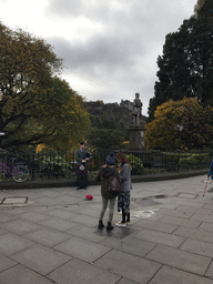 Bagpipe player at Princes Street, with a view on the statue of Allan Ramsay, the Princes Street Gardens and Edinburgh Castle