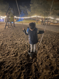 Max on a swing at the main playground at the Landal Coldenhove holiday park, by night