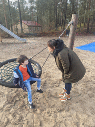 Miaomiao with bubble gum and Max on a swing at the main playground at the Landal Coldenhove holiday park, by night