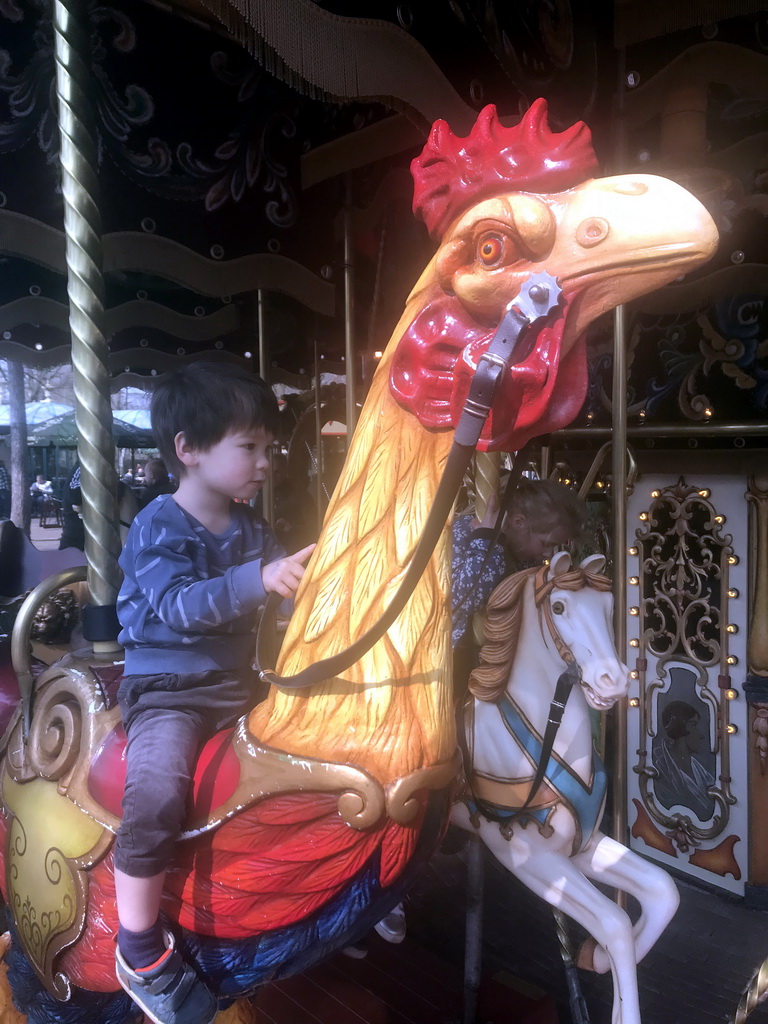 Max on a rooster statue at the Vermolen Carousel at the Anton Pieck Plein square at the Marerijk kingdom