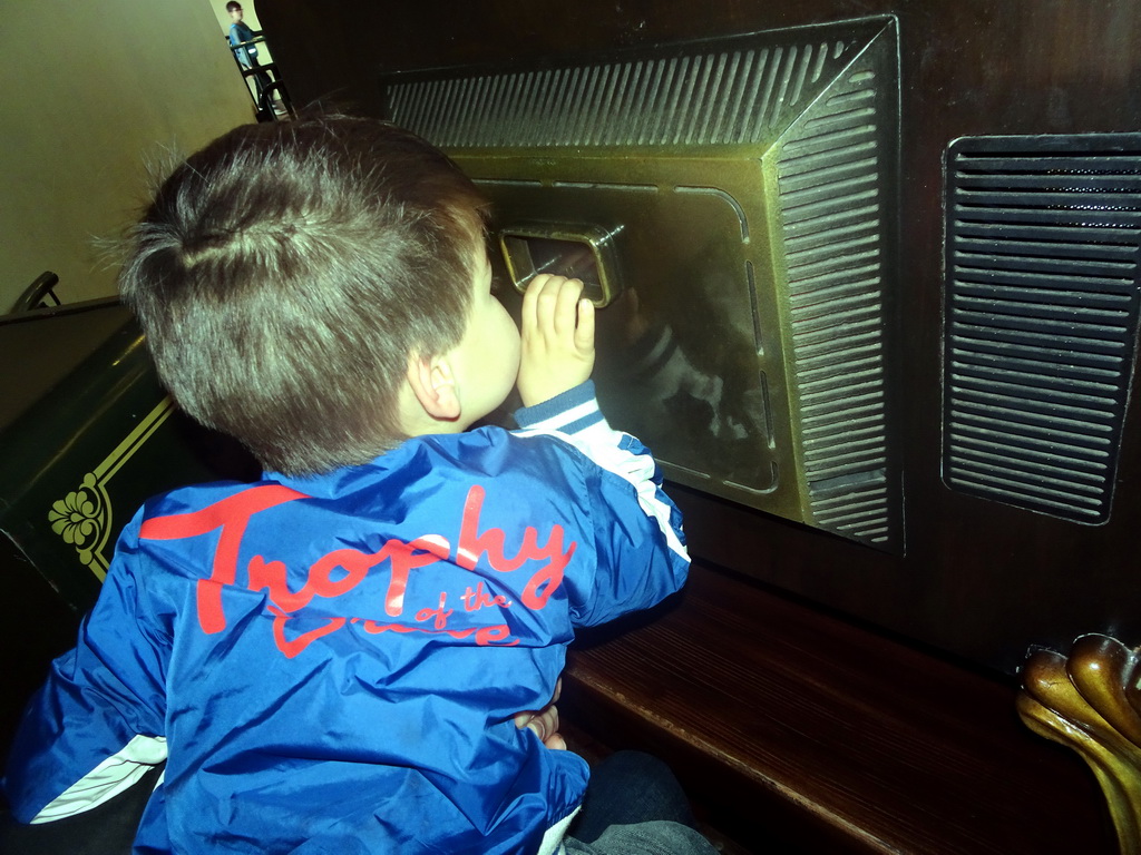 Max looking through the back side of the television at the waiting line for the Carnaval Festival attraction at the Reizenrijk kingdom