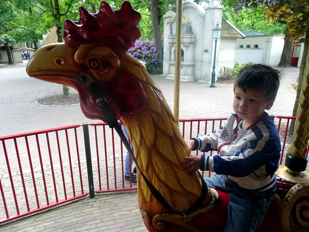 Max on a rooster statue at the Vermolen Carousel at the Anton Pieck Plein square at the Marerijk kingdom