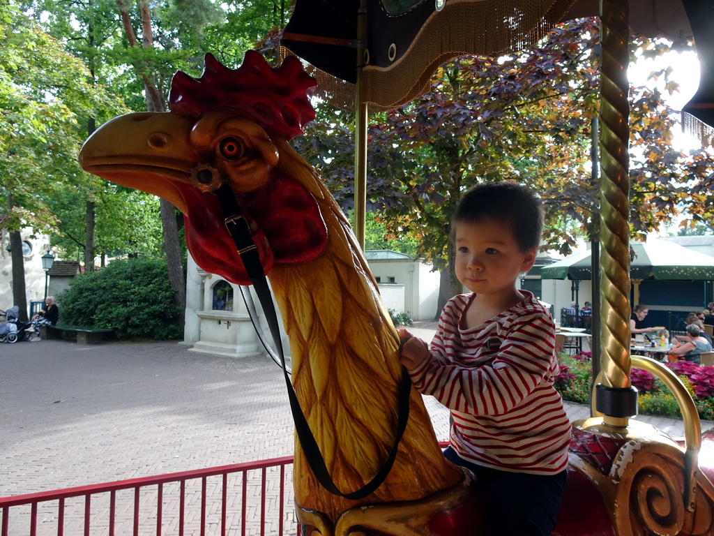 Max on a rooster statue at the Vermolen Carousel at the Anton Pieck Plein square at the Marerijk kingdom