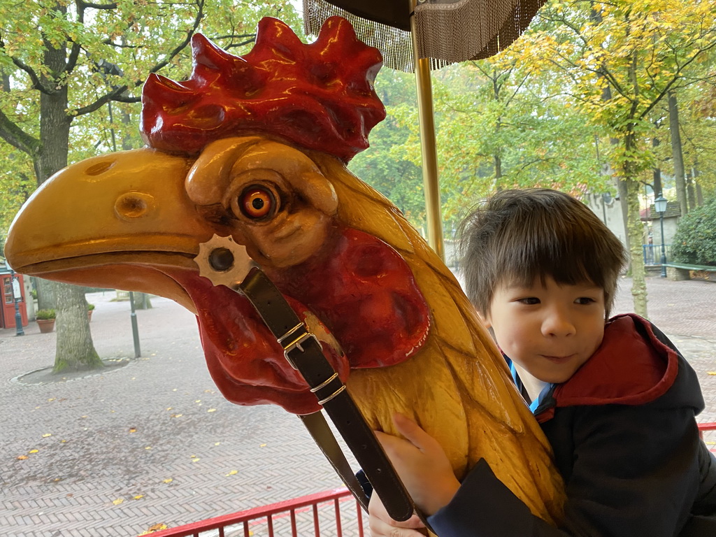 Max on a rooster statue at the Vermolen Carousel at the Anton Pieck Plein square at the Marerijk kingdom