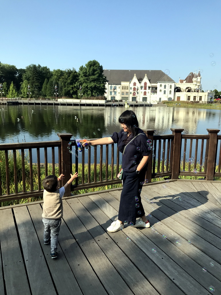 Miaomiao and Max playing with bubbles in front of the Aquanura lake and the Efteling Theatre at the Fantasierijk kingdom