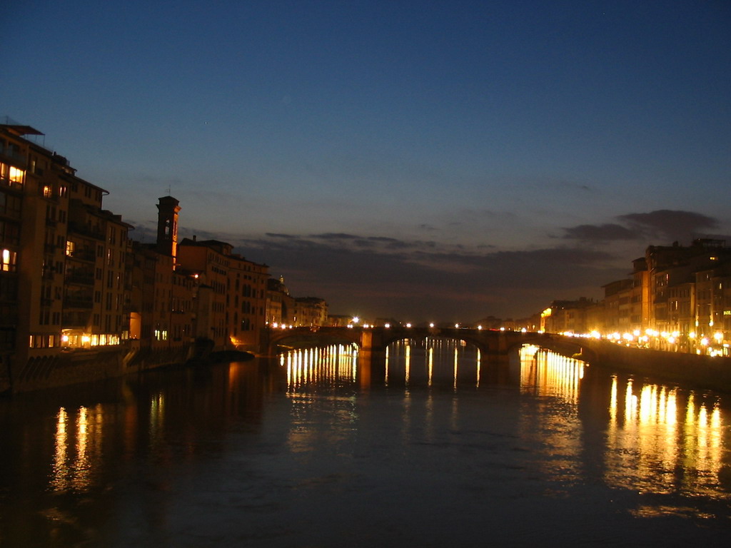 The Ponte Santa Trinita bridge over the Arno river and the tower of the Chiesa di San Jacopo Soprarno church, viewed from the Ponte Vecchio bridge, by night