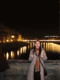 Miaomiao`s friend with an ice cream at the Ponte Vecchio bridge, with a view on the Ponte alle Grazie bridge over the Arno river, by night