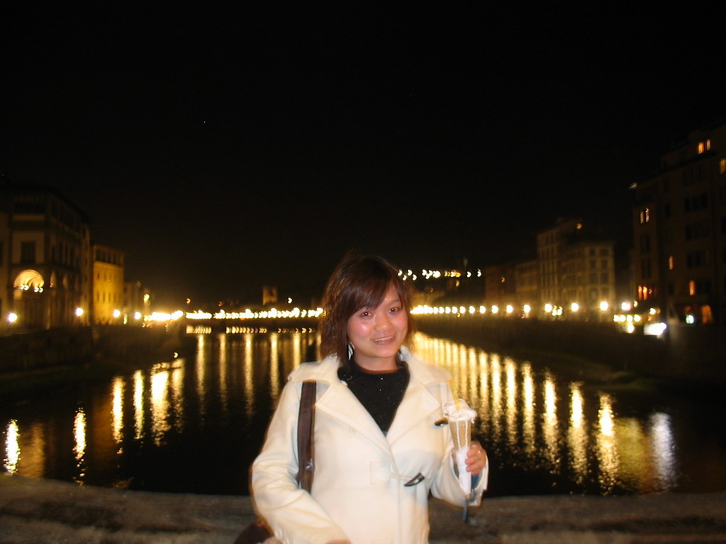 Miaomiao with an ice cream at the Ponte Vecchio bridge, with a view on the Ponte alle Grazie bridge over the Arno river, by night