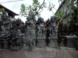 Shop with stone sculptures at the Jalan A. A. Gede Rai street, viewed from the taxi to Ubud
