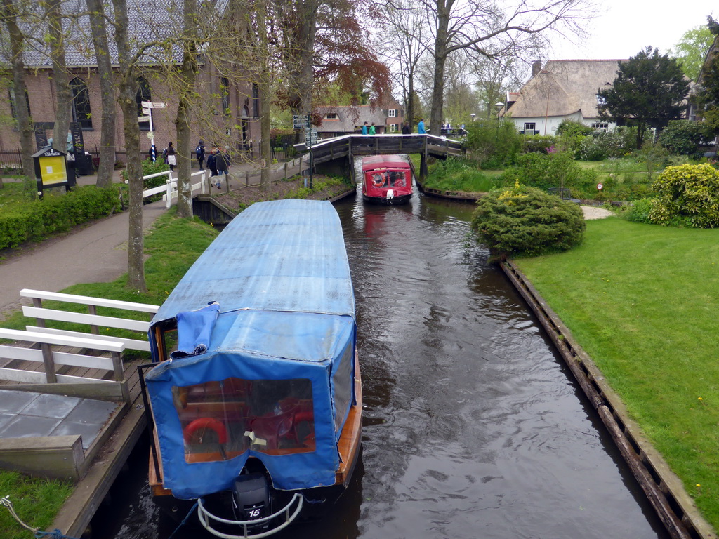 Boats, houses and bridges over the north side of the Binnenpad canal, and the Doopsgezinde Kerk Giethoorn church, viewed from a bridge over the Binnenpad canal