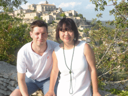 Tim and Miaomiao at a parking place next to the Route de Cavaillon, with a view on the southwest side of town with the Château de Gordes castle and the Église Saint Firmin church