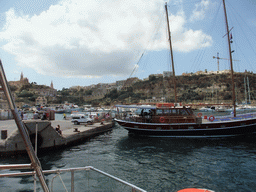 Boat at Mgarr Harbour and the town of Ghajnsielem with the Ghajnsielem Parish Church, from the Luzzu Cruises tour boat from Gozo to Comino