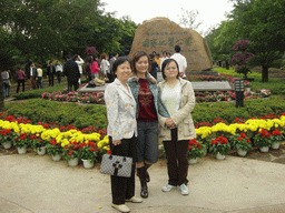 Miaomiao with her mother and sister in front of a rock with inscriptions at the entrance to the Hainan Volcano Park