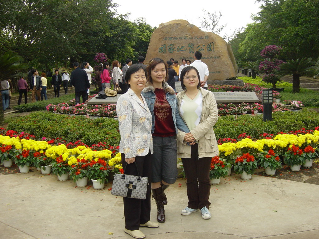 Miaomiao with her mother and sister in front of a rock with inscriptions at the entrance to the Hainan Volcano Park